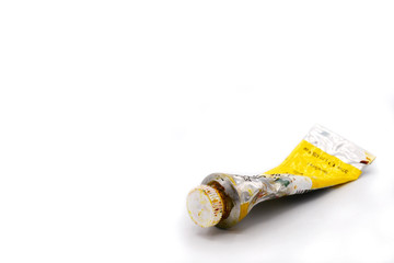 closed-up dried squeezed used yellow oil color tube for painting on a white background. original unique oil tube. painting equipment