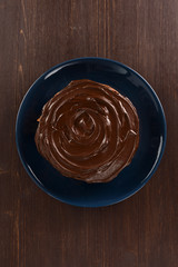 Tasty chocolate cake in dark blue plate on dark wooden table copy space