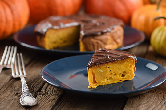 Delicious homemade pumpkin cake with chocolate icing served on dark blue plates with bright orange pumpkins