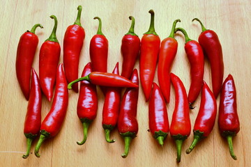 harvest autumn line from fresh cayenne red hot chili peppers on wooden table