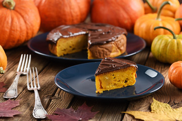 Pumpkin dessert. Delicious pumpkin cake with chocolate icing served with small bright orange pumpkins and marple leaves