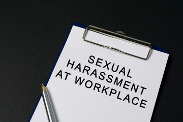 Sexual harassment at workplace word on paper - black background
