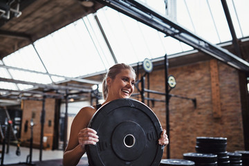Smiling young woman carrying weights for a gym workout