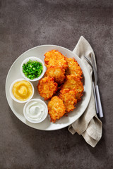 Potato pancakes, latkes or boxty and sauces from sour cream, yogurt, apple sauce and finely chopped green onion on grey stone background