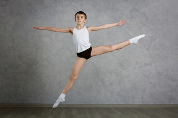 Little ballet caucasian boy dancing in a studio in white shirt and black underpants ballet uniform....