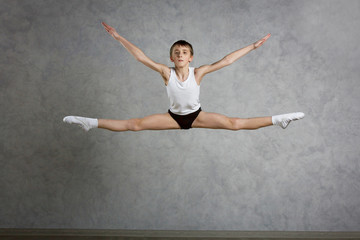 Little ballet caucasian boy dancing in a studio in white shirt and black underpants ballet uniform. Full-length portrait.