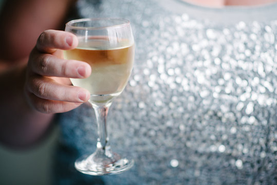 woman holds a glass of white wine as if to toast