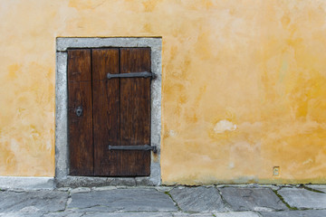 Old wooden small door on the yellow rustic wall