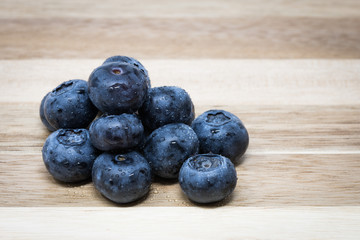 Close up of fresh Blueberries on wooden chopping board, sprayed with water.