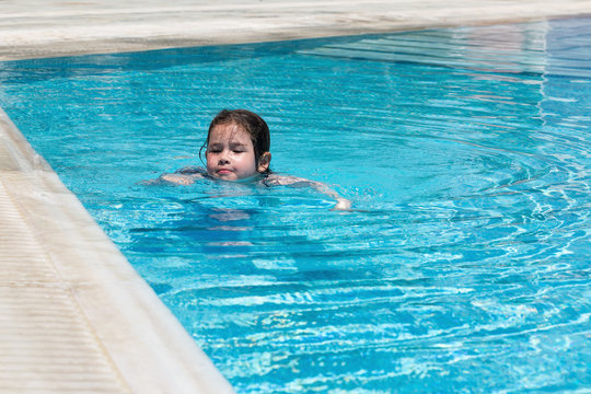 Happy little girl swimming in a pool