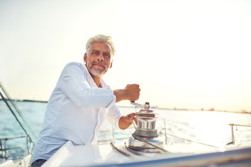 Mature man using winch on his boat while out sailing
