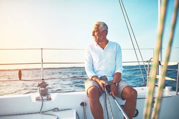 Wandaufkleber Mature man sailing his boat on the open ocean © Flamingo Images