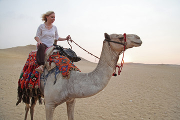 blonde Frau reitet auf einem Kamel in der Wüste von Ägypten