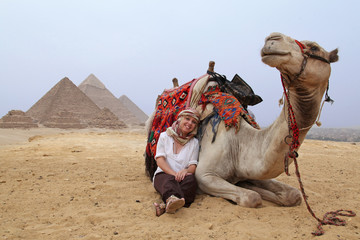 Kamel und Touristin aus der Froschperspektive vor den Pyramiden