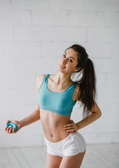 Fototapeta na wymiar Fitness, healthcare and dieting concept - beautiful sporty woman in aquamarine top and white shots with hand expander