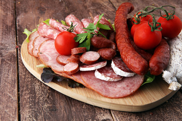 Food tray with delicious salami, pieces of sliced ham, sausage, tomatoes, salad and vegetable - Meat platter with selection - Cutting sausage and cured meat
