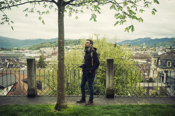 Retrato de turista en un parque de Lucerna, Suiza. Observando un &aacute;rbol y la naturaleza a su alrededor y con la ciudad de fondo.