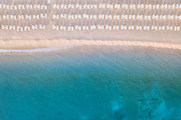 Beautiful beach, coast and bay with crystal clear sea water and loungers seen from above