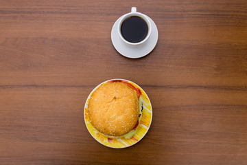 Delicious hamburger and cup of coffee on wooden table