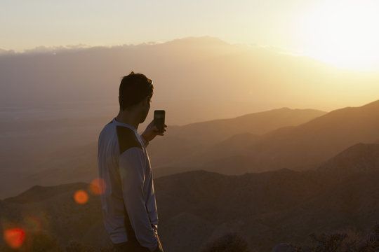 Young man looking out over a sunset from mountain viewpoint