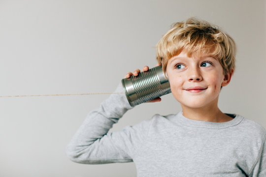 happy boy listens to his tin can phone