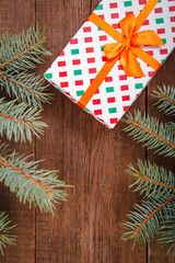 Christmas composition. Fir branches and a gift on a brown background. Space for text, top view. Background