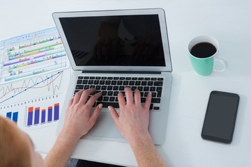 High angle view of businesswoman using laptop by various graphs