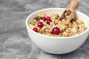 Granola muesli and cranberry berries for breakfast natural on a gray marble background with copy space, concept of a healthy diet