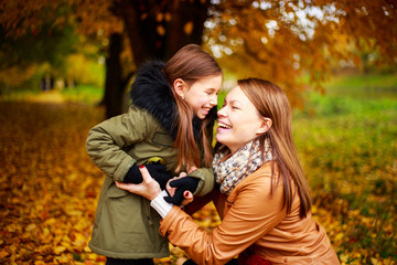 Happy family mother and child little daughter playing on autumn walk. Happy family. The school holidays.