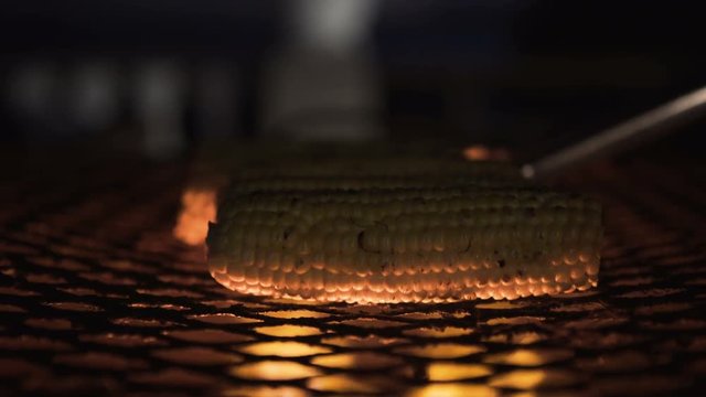 Close up corn cobs cooking on barbecue grill at beach hotel at night