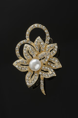 gold brooch flower with pearl isolated on black