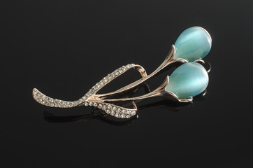 gold brooch flower with blue moon stone isolated on black