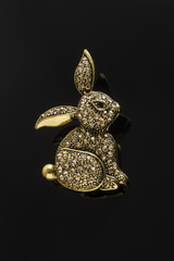 gold brooch bunny with diamonds isolated on black