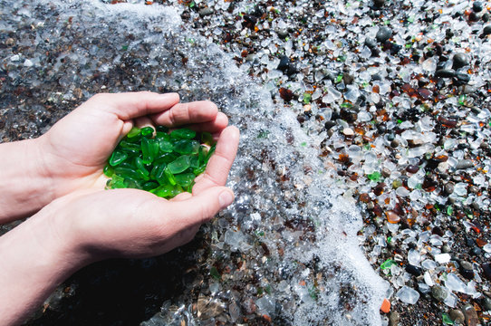 Womans hands hold up a collection of green sea glass