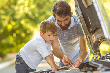 The boy and the father check the oil level in the car