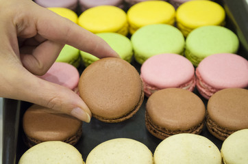 female hand taking tasty colorful macaroons from box