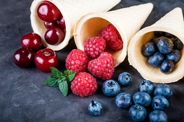 Waffle cones with fresh berries on a dark background close up