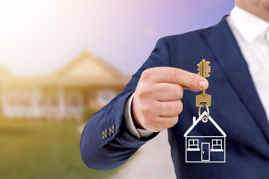 Real Estate Agent Holding Keys In Front Of A Beautiful New Home.