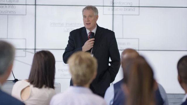  Business group listening to speaker giving a presentation at business seminar