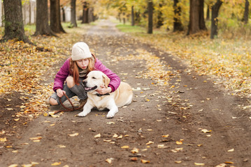 Portrait of a beautiful girl with her dog while walking in the autumn park