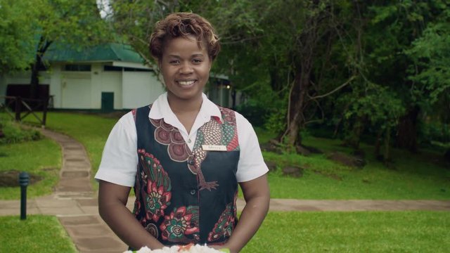 Portrait friendly smiling waitress serving cake to guest at holiday resort