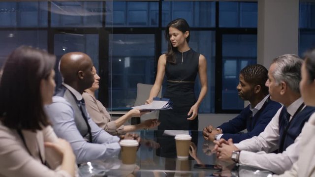  Businesswoman giving presentation to colleagues in late meeting