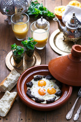 Sunnyside Eggs cooked in a Tajine dish with beef, Moroccan breakfast with juice and mint tea