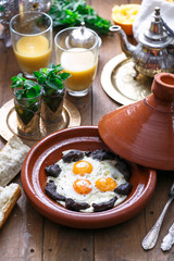 Sunnyside Eggs cooked in a Tajine dish with beef, Moroccan breakfast with juice and mint tea