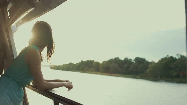  Beautiful woman relaxing on a boat at sunset, looking out across the water