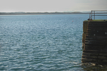 Fototapeta premium Harbour steps leading down to sea, in Cairnbulg, Scotland