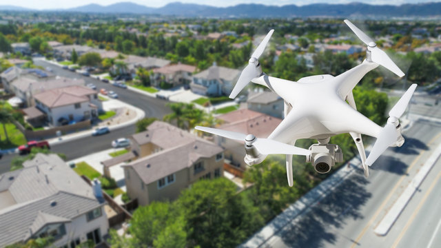 Unmanned Aircraft System (UAV) Quadcopter Drone In The Air Over Residential Neighborhood.