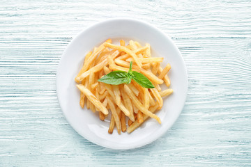 Plate with yummy french fries on wooden table