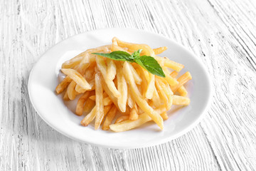 Plate with yummy french fries on wooden table