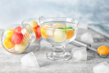 Glass of delicious cocktail with melon balls on table